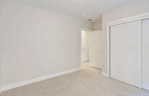 Unfurnished bedroom featuring light carpet and a closet