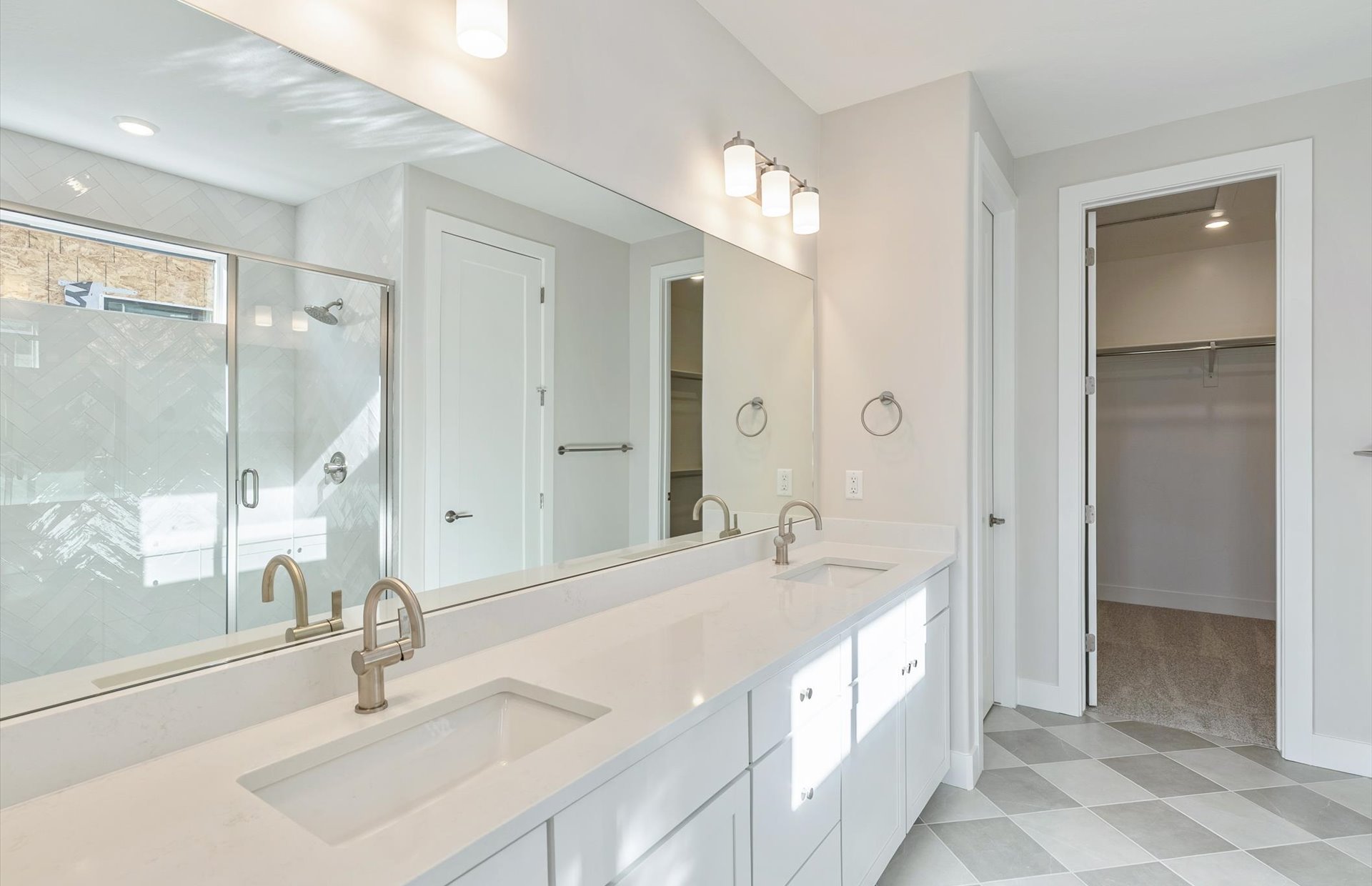 Bathroom with a spacious closet, double vanity, light floors, and a stall shower