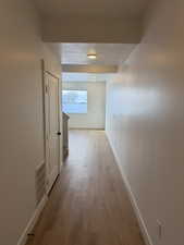 Corridor with light wood-type flooring and baseboards
