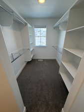 Walk in closet with dark carpet