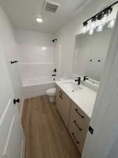 Bathroom with vanity, light wood-type flooring, and shower / washtub combination