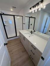 Bathroom featuring vanity, a stall shower, and light wood-style floors