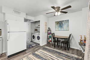 Kitchen featuring freestanding refrigerator, separate washer and dryer, white cabinetry, dark wood-style flooring, and ceiling fan