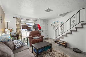 Living room with carpet floors, a textured ceiling, and crown molding
