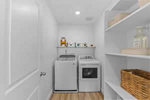 Laundry room with light wood-style floors and washing machine and dryer