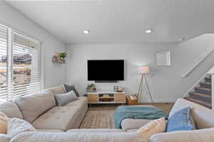 Living area with wood finished floors, recessed lighting, and a textured ceiling