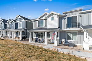 Rear view of property featuring board and batten siding, a lawn, and a balcony