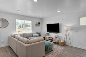 Living room featuring a textured ceiling, wood finished floors, and recessed lighting