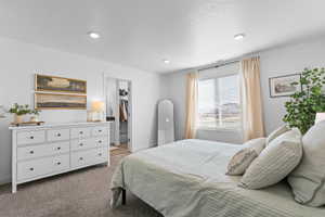 Bedroom featuring light carpet and a walk in closet