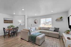 Living area with a textured ceiling, recessed lighting, and light wood-style floors