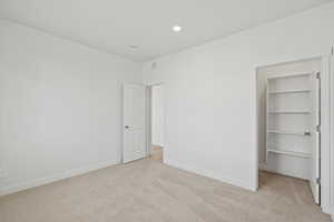 Unfurnished bedroom with a spacious closet and light colored carpet
