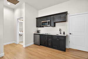 Casita living area featuring stainless steel appliances, light wood-style floors, light stone countertops, and dark cabinetry