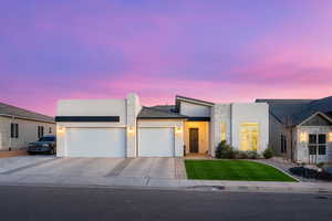 View of front facade featuring a garage, stucco siding, driveway, a front lawn, and stone siding