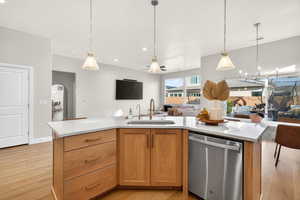 Kitchen with open floor plan, dishwasher, a kitchen island with sink, hanging light fixtures, and arched walkways