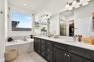 Primary ensuite bathroom featuring double vanity, a spacious closet, a bath, a shower stall, and light tile patterned floors