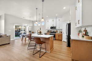 Dual tone kitchen with open floor plan, stainless steel appliances, two tone cabinets, a breakfast bar, and a center island with sink