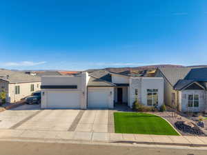 View of front of house with a garage, stucco siding, driveway, stone siding, and a front yard