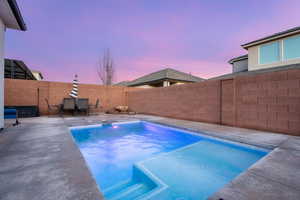 Pool at dusk featuring a patio, a fenced backyard, and outdoor dining area