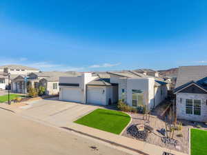 View of front facade featuring a residential view, an attached garage, driveway, stucco siding, and stone siding