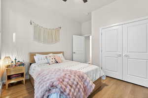 Bedroom with light wood-style floors, a closet, and a ceiling fan