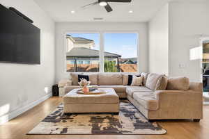 Living room with a ceiling fan, light wood-style flooring, and recessed lighting