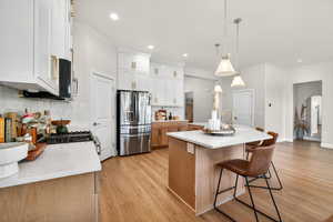 Kitchen with tasteful backsplash, a breakfast bar area, a kitchen island with sink, stainless steel appliances, and arched walkways