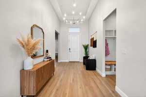 Entryway featuring suspended lighting, light wood-style flooring, and a high ceiling