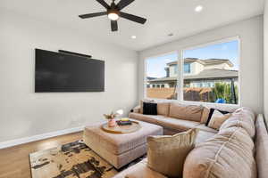 Living room with wood finished floors, recessed lighting, and a ceiling fan