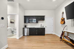 Casita with dark cabinets, light wood-style flooring, and stainless steel microwave, cooktop, sink and microwave