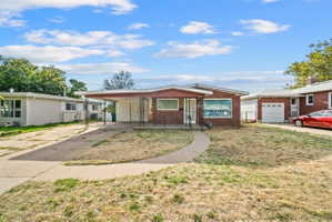 Ranch-style home featuring covered porch, brick siding, concrete driveway, an attached carport, and a front lawn