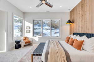 Bedroom featuring carpet floors, wooden walls, and ceiling fan