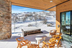 Snow covered patio featuring a mountain view and a patio