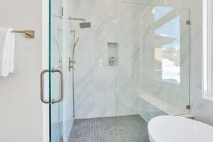 Bathroom with a freestanding tub and a marble finish shower
