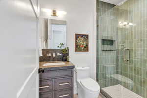 Full bath featuring vanity, a stall shower, and tasteful backsplash