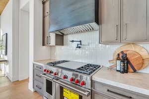 Kitchen with double oven range, light countertops, light wood-style flooring, and tasteful backsplash