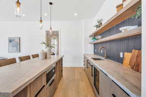 Kitchen featuring open shelves, modern cabinets, light stone counters, and decorative light fixtures