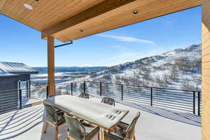 Snow covered patio with a patio, outdoor dining space, and a mountain view