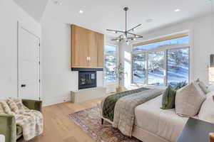 Bedroom featuring suspended lighting, light wood finished floors, and a fireplace