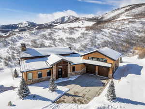 View of front facade with stone siding, a chimney, a mountain view, concrete driveway, and a garage