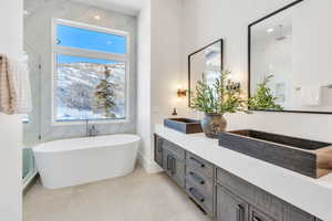 Full bath featuring double vanity, a soaking tub, and a marble finish shower