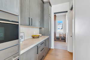 Kitchen featuring light wood finished floors, gray cabinets, and decorative backsplash