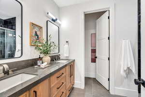 Full bathroom with double vanity, a shower stall, and light tile patterned floors