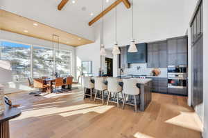 Kitchen featuring a kitchen breakfast bar, hanging light fixtures, an island with sink, backsplash, and light wood finished floors