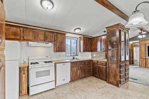 Kitchen with white appliances, light countertops, ceiling fan, tasteful backsplash, and vaulted ceiling