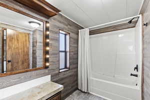 Bathroom featuring vanity, a textured ceiling, and shower / bathtub combination with curtain