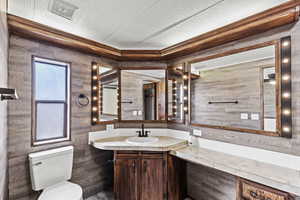 Half bath with vanity, a textured ceiling, and ornamental molding