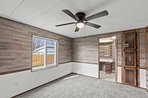 Empty room featuring light colored carpet, a textured ceiling, and a ceiling fan