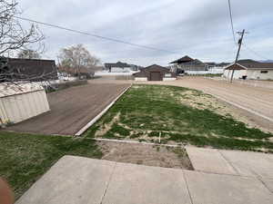 View of grassy yard with an outdoor structure, a residential view, and dirt driveway