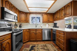 Kitchen featuring stainless steel appliances, wood finish cabinets, a peninsula, dark wood-type flooring, and a textured ceiling