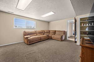 Carpeted living room featuring a textured ceiling and baseboards